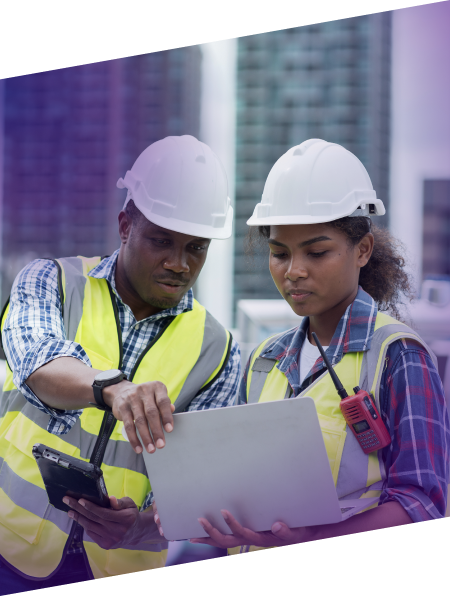 two construction workers working on-site with a laptop