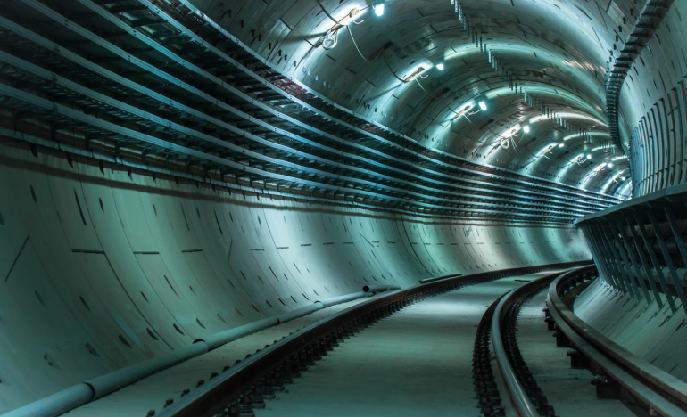 lighted tunnel with train track in the middle