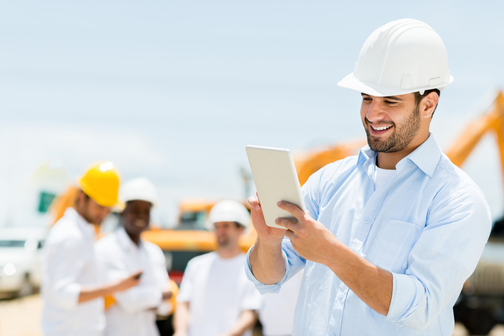 male engineer at a construction site looking at a tablet